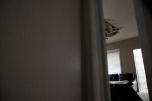 partial view of ceiling damage from burst pipe visible in corner of room