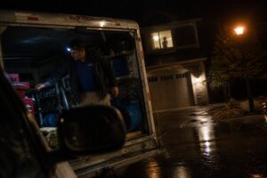 technician retrieving equipment from service truck during emergency water damage response at night in South Jordan Utah