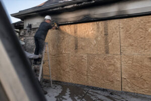 technician installing board up panels on fire damaged garage to secure property after fire