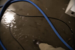 floor with dark water and hose partially visible during sewage cleanup