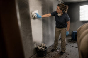 technician cleaning soot from wall using dry sponge during smoke damage restoration in Utah home