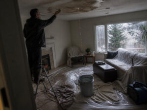 technician inspecting ceiling leak and water damage inside home after storm in Utah