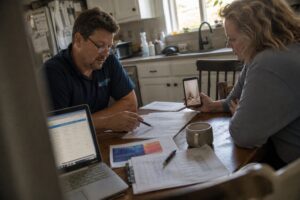 technician reviewing water damage insurance claim documents with homeowner at kitchen table in South Jordan Utah