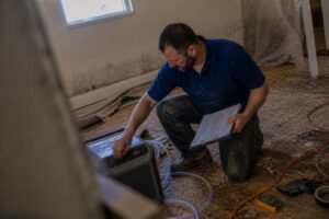 technician adjusting dehumidifier and checking moisture readings on damaged basement subfloor in South Jordan Utah
